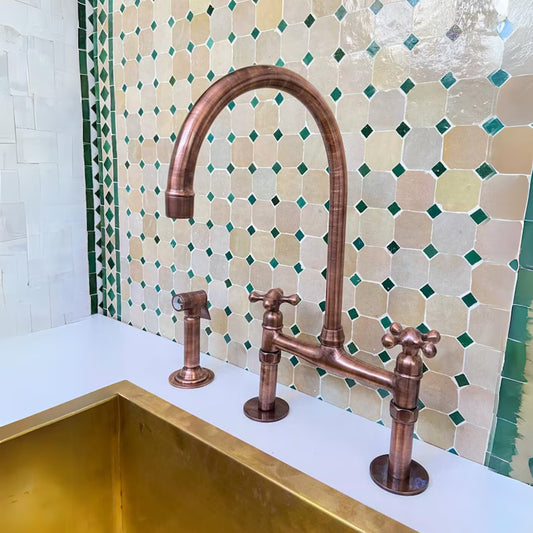Modern Copper Kitchen Faucet with vintage finish, handcrafted design, and matching side handles installed above a gold sink with patterned tile backsplash.