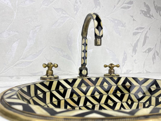 Vintage Brass Bathroom Faucet with Geometric Detailing by Brasska, featuring black and gold patterns on the sink and brass fixtures.