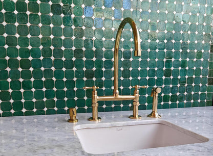 Bridge kitchen faucet with side sprayer in unlacquered brass finish, made of durable brass with modern design for kitchen use.