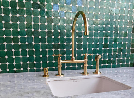 Bridge kitchen faucet with side sprayer in unlacquered brass finish, made of durable brass with modern design for kitchen use.