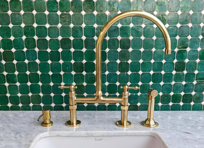 Bridge kitchen faucet with side sprayer in unlacquered brass finish, featuring durable metal construction and modern design.
